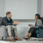 Seorang pewawancara dan narasumber melakukan sesi wawancara tatap muka di ruang kantor modern