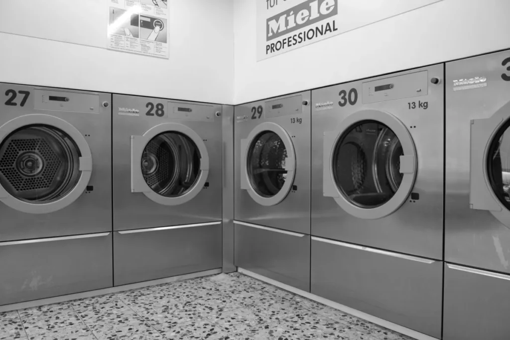 Deretan mesin cuci industri di laundromat modern yang rapi dan bersih