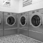 Deretan mesin cuci industri di laundromat modern yang rapi dan bersih